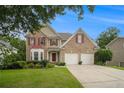 Charming brick home with manicured lawn, two-car garage, and lovely tree lined street at 5925 Crescent Landing Dr, Cumming, GA 30028