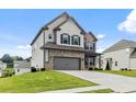This home boasts a brick and gray siding exterior with an attached garage, complemented by a lush lawn and inviting curb appeal at 1494 Weeping Tree Cir, Auburn, GA 30548