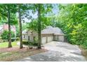 View of brick home showcasing an attached two-car garage surrounded by lush greenery and mature trees at 920 Waters Reach Ct, Alpharetta, GA 30022