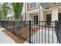 Charming exterior view of a townhouse with brick facade, black wrought iron fence, and landscaped front yard at 344 Olmstead Way # 32, Alpharetta, GA 30022
