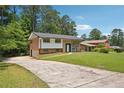 Charming brick home with an inviting driveway, well-manicured lawn and mature trees on a sunny day at 3611 Radcliffe Blvd, Decatur, GA 30034