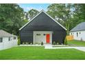 Charming exterior elevation of a modern home with black siding, a bright orange front door and a well manicured lawn at 587 Woods Nw Dr, Atlanta, GA 30318