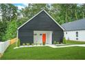 Charming exterior elevation of a modern home with black siding, a bright orange front door and a well manicured lawn at 587 Woods Nw Dr, Atlanta, GA 30318