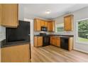 Bright kitchen featuring wood cabinets, black appliances, and a view of the backyard at 1025 Pebble Creek Trl, Suwanee, GA 30024