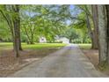 View down long paved driveway, leading to home with a detached garage and surrounded by mature trees and landscaped lawn at 3100 Meadow Trl, Loganville, GA 30052