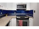 Modern kitchen features stainless steel appliances, granite counters and stylish blue tiled backsplash at 1421 Peachtree Ne St # 401, Atlanta, GA 30309