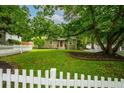 Quaint home with a lush green lawn, mature trees, and a white picket fence at 1734 8Th St, Brookhaven, GA 30341