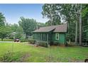 Charming green home with a cozy screened-in porch and lush, landscaped yard surrounded by mature trees at 3743 Wyntuck Nw Cir, Kennesaw, GA 30152
