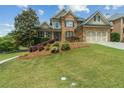 Beautiful brick home featuring a well-manicured lawn, shrubbery, and a two-car garage at 1408 Chloe Dr, Lawrenceville, GA 30043