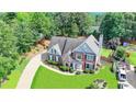 Aerial view of brick home with lush lawn, mature trees, and long driveway at 189 Azalea Chase Dr, Suwanee, GA 30024