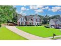 Two-story brick home boasts an expansive lawn, a long driveway, and neat landscaping at 189 Azalea Chase Dr, Suwanee, GA 30024