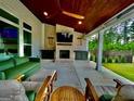 Inviting outdoor living space with fireplace, comfortable seating, ceiling fan, and views of the backyard at 247 Widener Way, Peachtree City, GA 30269