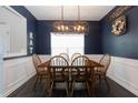 Dining room with dark blue walls, wainscoting, modern light fixture and seating for six at 137 Prominence Ct, Canton, GA 30114