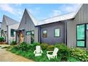 Charming home featuring a metal roof, gray vertical siding, an orange door and inviting front lawn with two white chairs at 10862 Serenbe Ln, Chattahoochee Hills, GA 30268