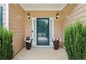 Close-up of the front door and porch area featuring flower pots and sconce lighting at 4204 Woodfare Nw Ln, Kennesaw, GA 30152