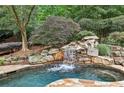 Backyard pool with waterfall feature surrounded by mature trees at 145 Ardsley Ln, Alpharetta, GA 30005