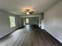Bright living room with gray vinyl flooring, ceiling fan, and large windows providing natural light at 15 Fontana Ct, Covington, GA 30016