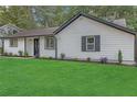 Charming single-story home with a lush green lawn, white siding, black trim, and neatly manicured landscaping at 373 Hemlock Dr, Lawrenceville, GA 30046