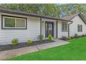 Inviting home entrance with a black front door, white siding, well-kept lawn, and manicured landscaping at 373 Hemlock Dr, Lawrenceville, GA 30046