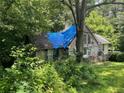 A-frame home sitting on a wooded lot and covered by a blue tarp at 590 Killian Road Rd, Canton, GA 30114