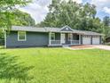 Inviting single-story home with a quaint front porch and two-car garage, surrounded by a well-kept lawn and mature trees at 4720 Hull Rd, Conyers, GA 30094