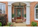 Inviting front entrance with a wood door, decorative plants, and stylish outdoor lighting at 335 Scarborough Way, Alpharetta, GA 30022