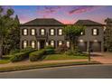 Elegant two-story home with a brick facade, manicured landscaping, and a two-car garage at dusk at 3015 Southmoor Trce, Roswell, GA 30075
