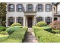 Elegant home exterior featuring stone accents, arched windows, dark shutters, and manicured shrubbery at 3015 Southmoor Trce, Roswell, GA 30075