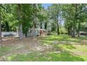 Quaint home with brick facade, a red front door, surrounded by mature trees and green lawn at 200 Robin Hood Ln, Hampton, GA 30228