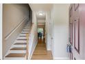 Bright foyer featuring hardwood floors, staircase with white railing, and a view into the dining area at 1727 Shire Village Dr, Sugar Hill, GA 30518