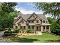 Elegant home featuring a manicured lawn, stone accents, and a welcoming covered porch at 930 Shepards Ct, Roswell, GA 30075