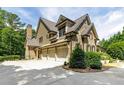 Spacious three-car garage with stone and siding exterior, complemented by mature landscaping at 930 Shepards Ct, Roswell, GA 30075