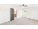 Bedroom with ceiling fan, neutral carpet and walls, window overlooking yard, and an open bathroom doorway at 102 Red Oak Ln, Carrollton, GA 30116