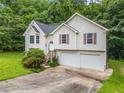 Two-story home with a lush green front lawn, a two-car garage, and surrounded by mature trees offering privacy at 87 Fair Havens Dr, Hiram, GA 30141