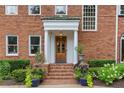 Charming front entrance with stately columns, a wooden door, and beautifully arranged potted plants at 1036 Oxford Ne Rd, Atlanta, GA 30306