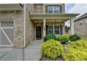 Charming brick home featuring a cozy front porch with decorative columns and manicured landscaping at 2090 Harvester Ln, Buford, GA 30518