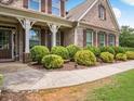 Charming front porch featuring brick accents, columns, lush shrubbery, and a cozy walkway at 3315 High Noontide Nw Way, Acworth, GA 30101