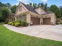 Spacious two-car garage of a brick house with manicured bushes in front and a concrete driveway at 3315 High Noontide Nw Way, Acworth, GA 30101