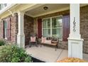 Cozy front porch with a bench, rocking chair, brick accents, and meticulously landscaped surroundings at 1626 Waterchase Dr, Dacula, GA 30019