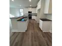 Stylish kitchen with white cabinets, black countertops, island and modern appliances at 3867 Lockaby Way, Lawrenceville, GA 30044