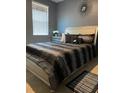 Elegant bedroom with a silver-trimmed bed, dark bedding, and a modern starburst mirror, creating a stylish retreat at 11547 Hathaway Dr, Hampton, GA 30228