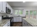 Bright kitchen boasts stainless appliances, granite counters, and a view to backyard at 1790 Abinger Ln, Lawrenceville, GA 30043