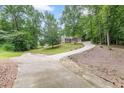 Long concrete driveway leading up to a lovely home surrounded by lush trees and landscaping at 3329 Walt Stephens Rd, Stockbridge, GA 30281
