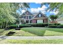 Beautiful two-story brick home with a manicured lawn and a welcoming front porch with beautiful bushes at 4770 Spring Park Cir, Suwanee, GA 30024