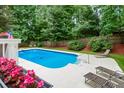 Refreshing backyard pool area complete with lounge chairs, flower pots and views of the privacy fence and surrounding trees at 215 Ansley Ct, Roswell, GA 30076