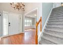 Bright foyer with hardwood floors, white door, staircase, and chandelier, creating a welcoming entry at 3554 Cherry Blossom Court, Loganville, GA 30052