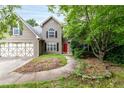 Inviting two-story home featuring neutral siding, two-car garage, red front door, and mature landscaping at 3554 Cherry Blossom Court, Loganville, GA 30052