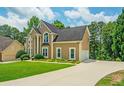 Charming two-story home with manicured lawn and long driveway to the side-entry garage, surrounded by mature trees at 2521 Wood Creek Ct, Dacula, GA 30019