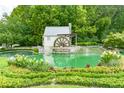 Scenic community pond featuring a decorative water wheel, landscaping, and lush greenery at 2934 Mill Grove Ter, Dacula, GA 30019