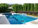 Backyard featuring a luxurious in-ground pool with a spa, waterfall feature, and surrounding patio at 904 Urban Ash Ct, Johns Creek, GA 30022
